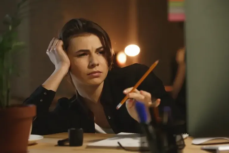 Person at a desk with their head in their hands after a long working day