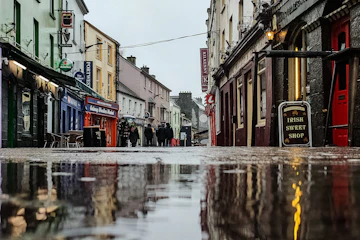 Wet grey street with a puddle on a rainy winter day in Galway